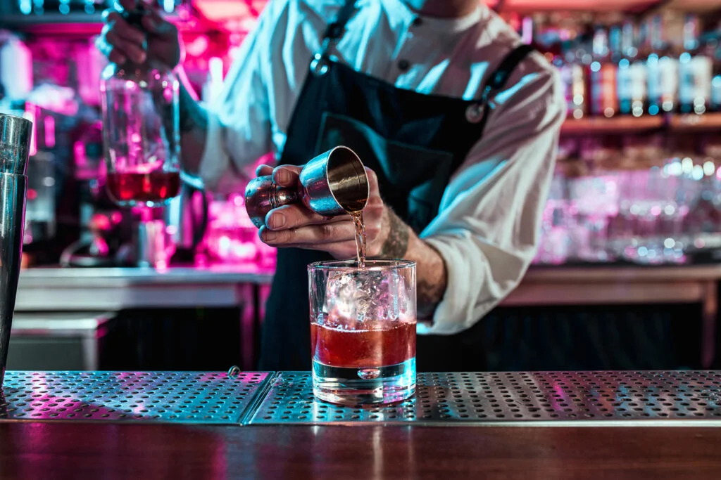 A bartender pouring a cocktail